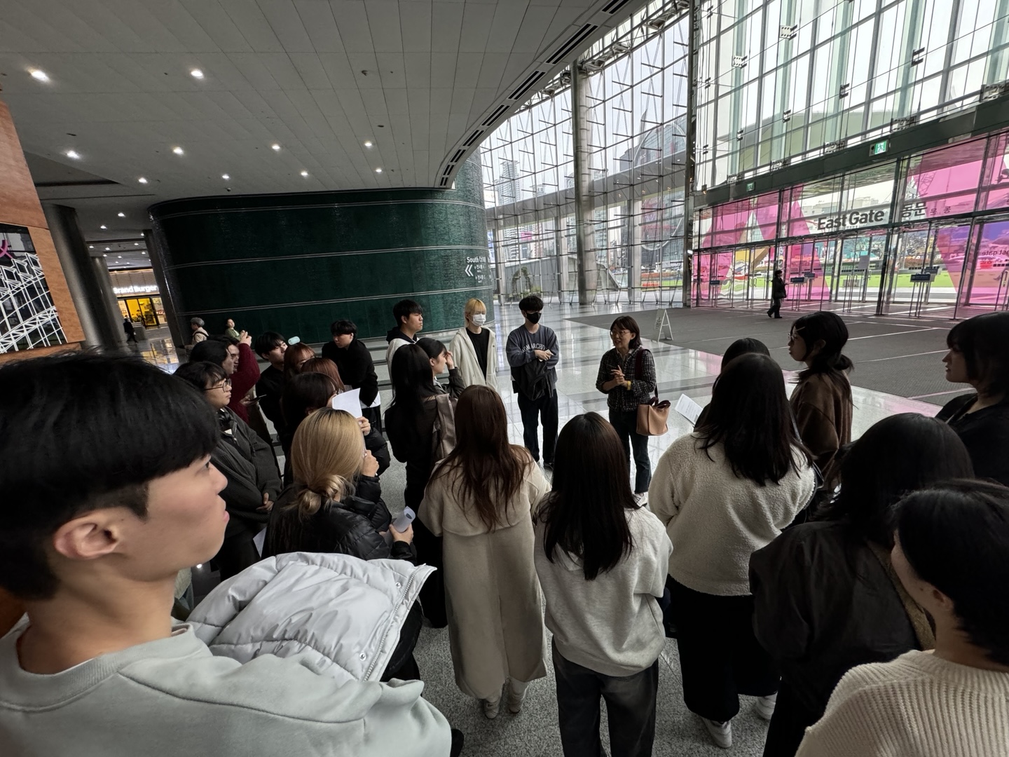 학생들이 교수님 근처에 모여서 교수님 말씀을 듣고 있다